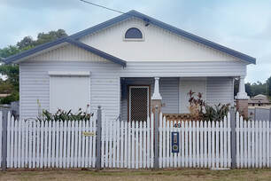 Photo of Deakin House. Pale blue timber house with dark blue trims.